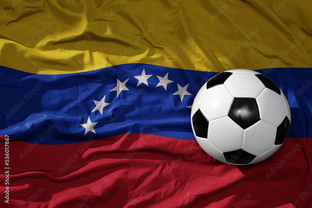 Naklejka premium vintage football ball on the waveing national flag of venezuela background. 3D illustration