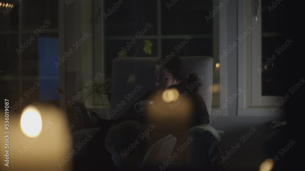 Rising energy prices in Europe, mother sits in dark room lit by candles in European family home Rising energy prices in Europe, mother sits in dark room lit by candles in European family home