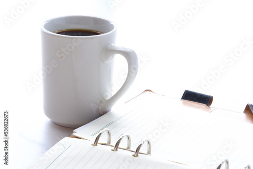 コーヒーを飲みながらリング式のシステム手帳でスケジュール調整