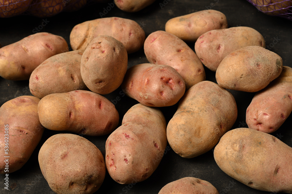 a pile of potatoes on a dark wooden background a pile of potatoes on a dark wooden background