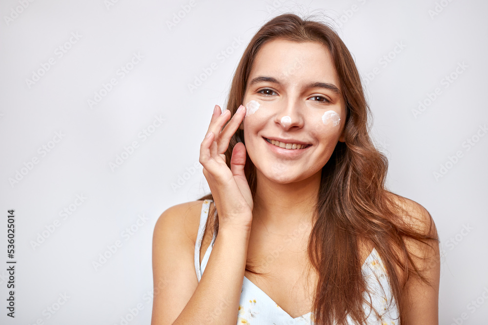 A beautiful girl applies moisturizing cream to her face. A beautiful girl applies moisturizing cream to her face.