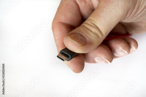 Hand holding a usb-c type cabel on a whith background, selective focus, macro, close-up