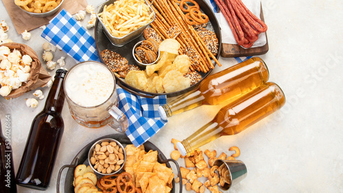 Assortment of beer and salty snacks on light background.