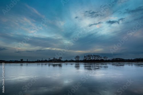 Picturesque evening clouds over the frozen lake © darekb22