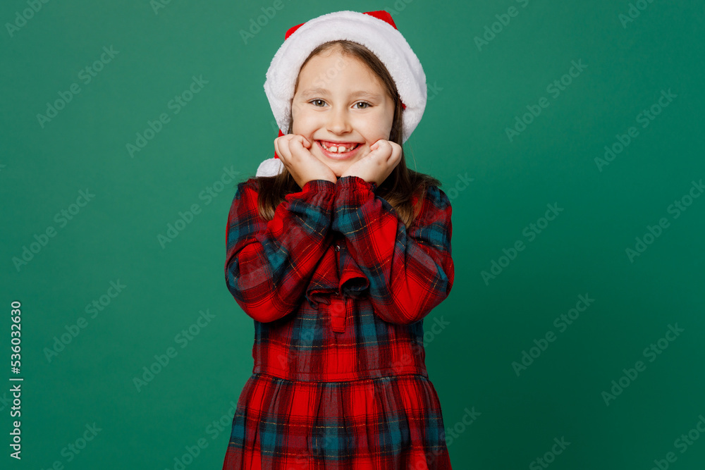 Merry smiling happy satisfied little child kid girl 6-7 years old wear red dress Christmas hat posing look camera prop up hold face isolated on plain dark green background Happy New Year 2023 concept Merry smiling happy satisfied little child kid girl 6-7 years old wear red dress Christmas hat posing look camera prop up hold face isolated on plain dark green background Happy New Year 2023 concept
