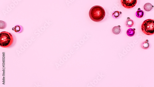 Pastel pink copy space background with red and pink shiny ornaments . Flat lay Christmas concept