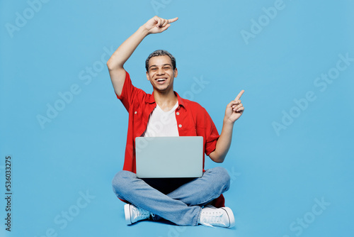 Fototapeta Full body young IT man of African American ethnicity ijn red shirt hold use work