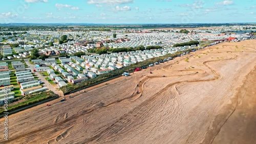 Long sandy beach shot with drone showing sea, sand, holiday homes and a racing track created in the sand dunes with Motorbikes racing. Lincolnshire, England. Ingoldmells motocross photo