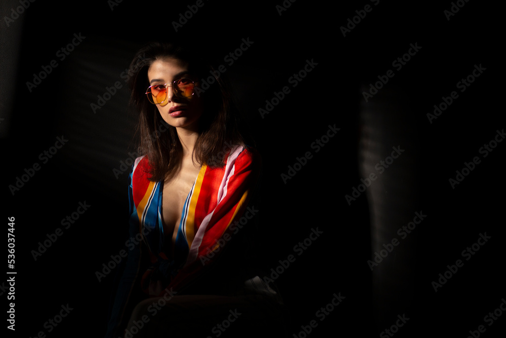 Portrait of a young brunette young woman in colorful clothes and orange sunglasses, with closed eyes. Space for text. Portrait of a young brunette young woman in colorful clothes and orange sunglasses, with closed eyes. Space for text.