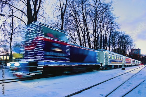 Kyiv, Ukraine-January 22, 2022:Blurred Christmas illuminated train. Train arrived at the station. Holiday decorations of train. Narrow gauge Kyiv Children's Railway in Syretsky Park photo