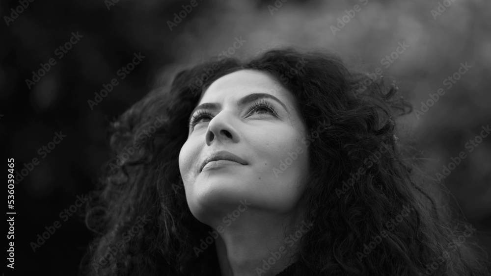 Woman standing outdoors in contemplation in monochromatic. Black and white artistic clip of 30s female person staring up at SKY