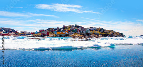 Panoramic view of colorful Kulusuk village in East Greenland - Kulusuk, Greenland - Melting of a iceberg and pouring water into the sea - Drummer statue in the foreground