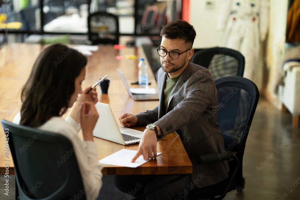 Businessman gives businesswoman dismissal contract to sign. Businessman gives businesswoman dismissal contract to sign.