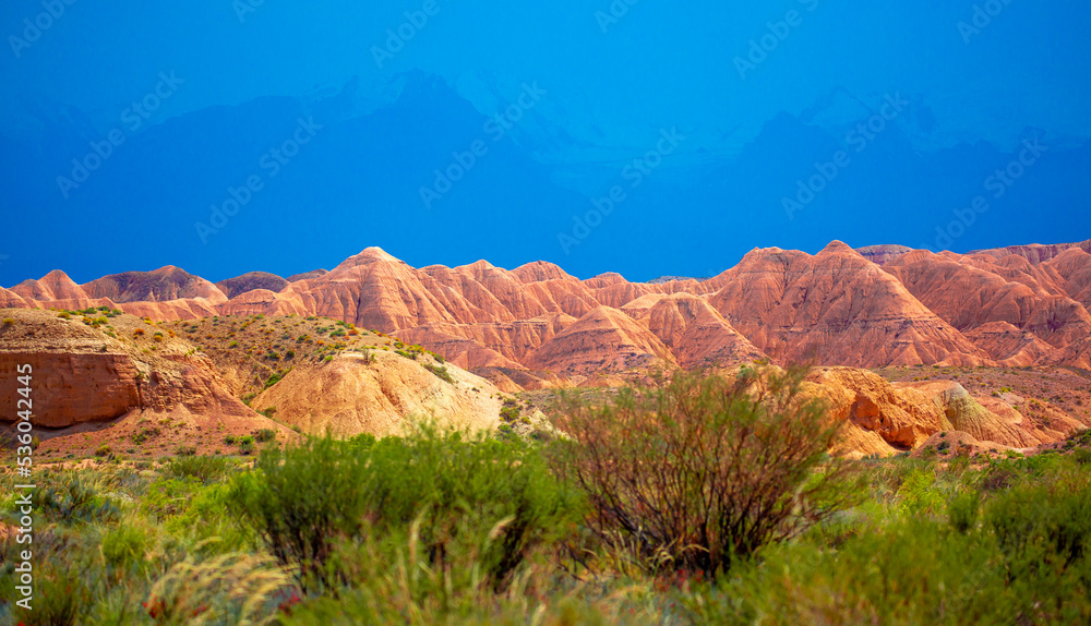 Natural unusual landscape of red rocks against the backdrop of blue mountains. The extraordinary beauty of nature is similar to the Martian landscape. Amazingly beautiful landscape.