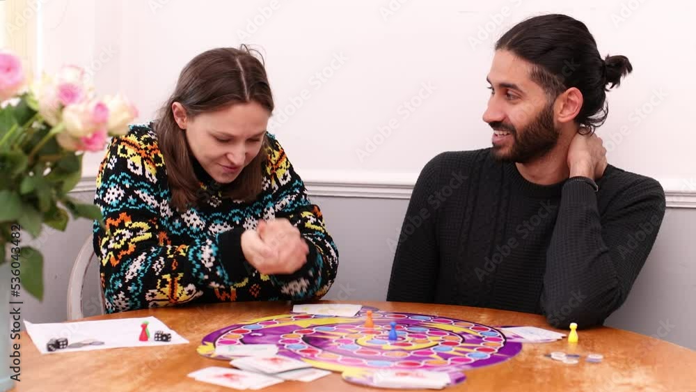 South Asian man playing board game with young white woman who is smug after her move South Asian man playing board game with young white woman who is smug after her move