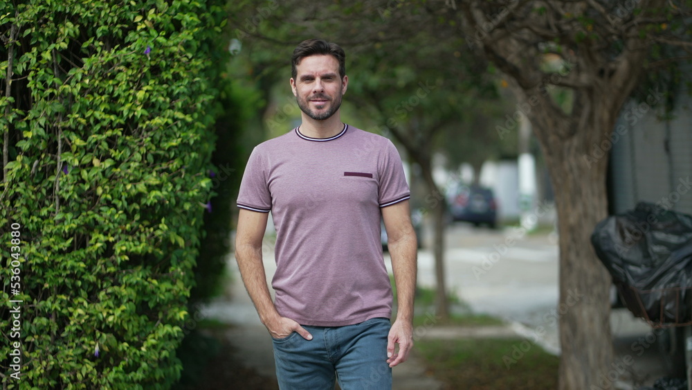 One confident man in 30s walking toward camera smiling. Handsome male person in city street sidewalk with casual clothing One confident man in 30s walking toward camera smiling. Handsome male person in city street sidewalk with casual clothing