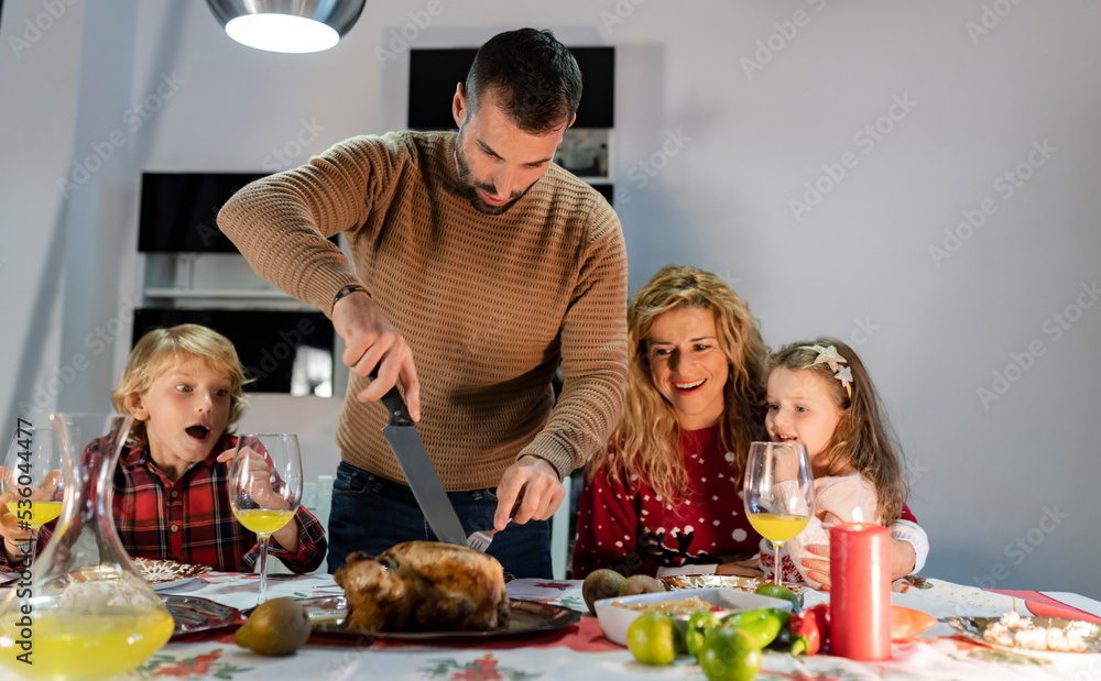 family having christmas dinner at home. dad carves the turkey. - focus on man -