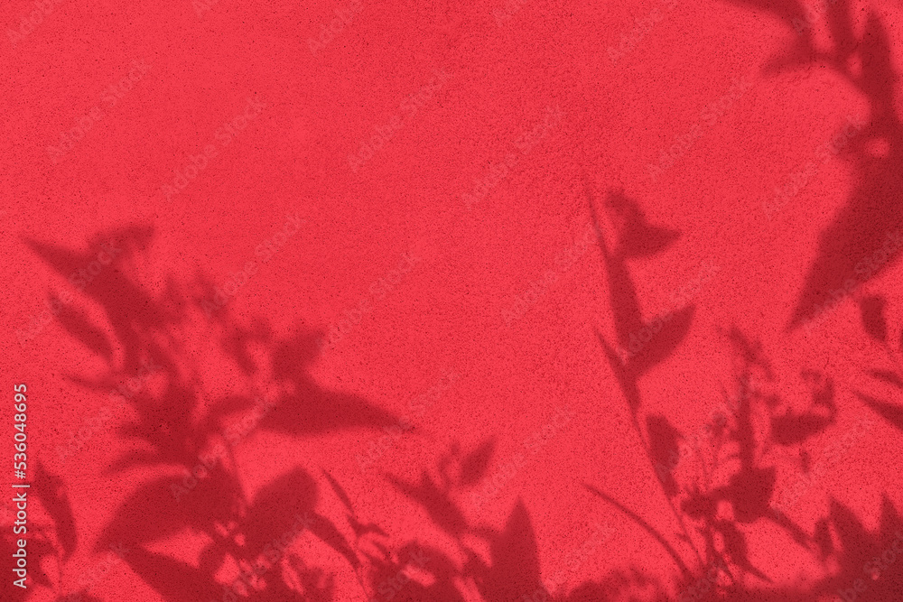 Obraz premium Shadow of leaves on bright red concrete wall texture with roughness and irregularities. Abstract trendy colored nature concept background. Copy space for text overlay, poster mockup flat lay 