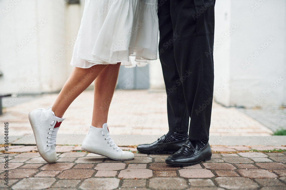 Close up view of legs on the ground. Beautiful bride with his fiance is celebrating wedding outdoors Close up view of legs on the ground. Beautiful bride with his fiance is celebrating wedding outdoors