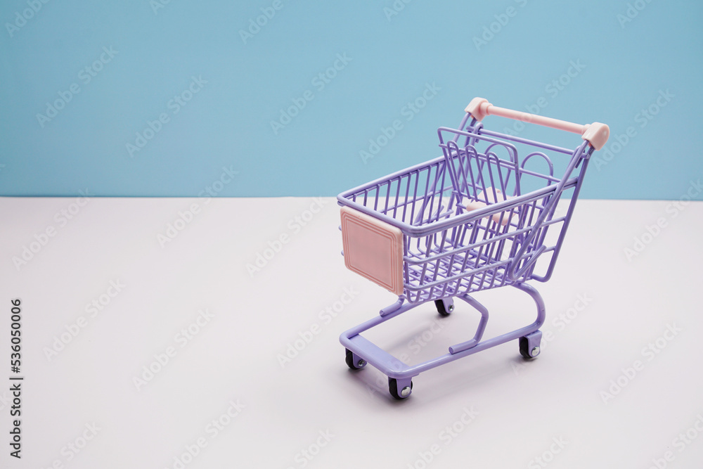 Purple trolley shopping cart with space copy on blue and pink background