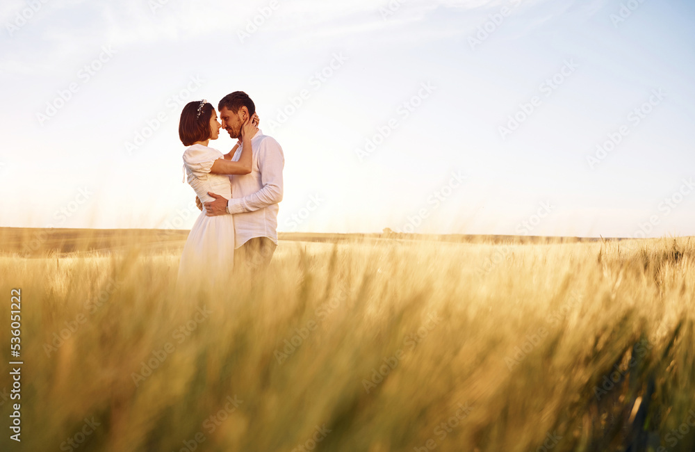 Standing and embracing. Couple just married. Together on the majestic agricultural field at sunny day Standing and embracing. Couple just married. Together on the majestic agricultural field at sunny day