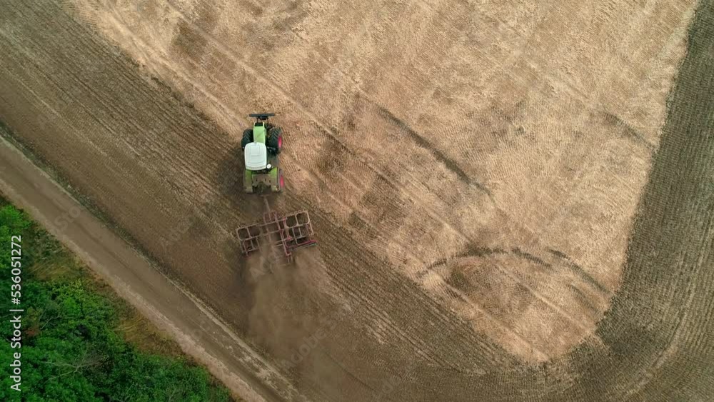 Drone view of a tractor plows the land after harvesting wheat. The tractor turns around. Top down shot. Drone view of a tractor plows the land after harvesting wheat. The tractor turns around. Top down shot.