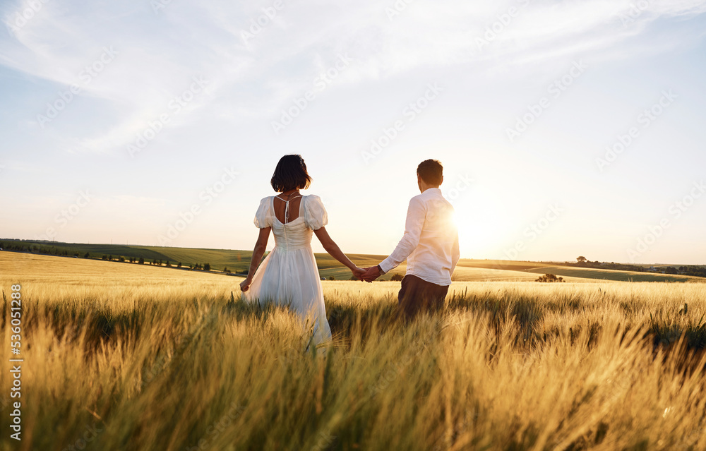 Walking and holding each other by the hands. Couple just married. Together on the majestic agricultural field at sunny day Walking and holding each other by the hands. Couple just married. Together on the majestic agricultural field at sunny day