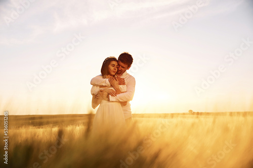Against beautiful landscape. Couple just married. Together on the majestic agricultural field at sunny day