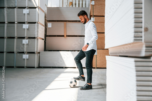 Taking a break, playing with soccer ball. Storage worker is in the warehouse with bunch of products © standret