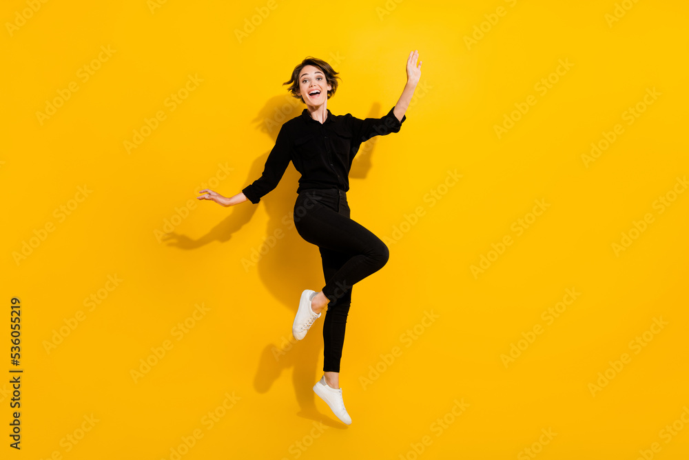 Photo of sweet adorable lady wear black shirt jumping high empty space isolated yellow color background