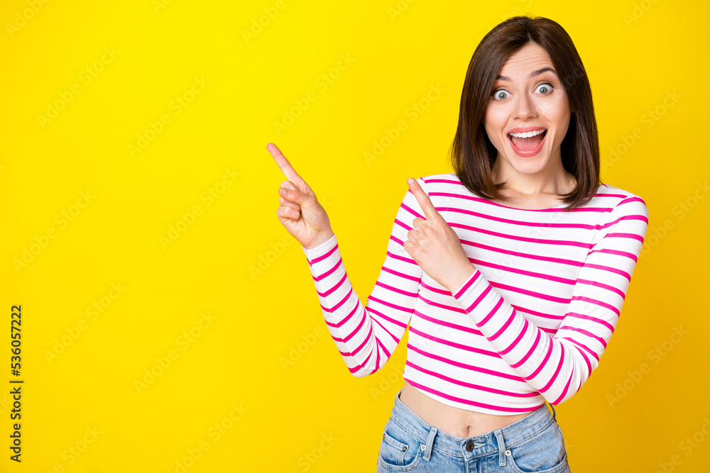 Closeup photo of young attractive girl pointing fingers empty space speechless great deal isolated on yellow color background Closeup photo of young attractive girl pointing fingers empty space speechless great deal isolated on yellow color background