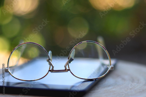 E-book reader and reading glasses in the garden. Selective focus.