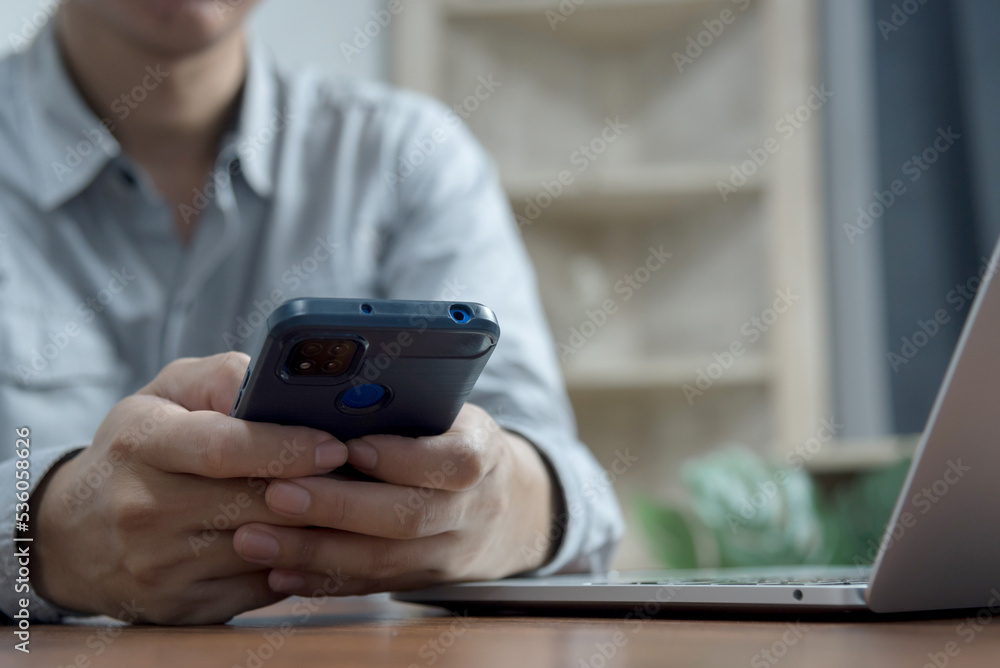 man hands using mobile phone and computer at office desk.Business working online communications e-commerce internet services at home office concept. man hands using mobile phone and computer at office desk.Business working online communications e-commerce internet services at home office concept.