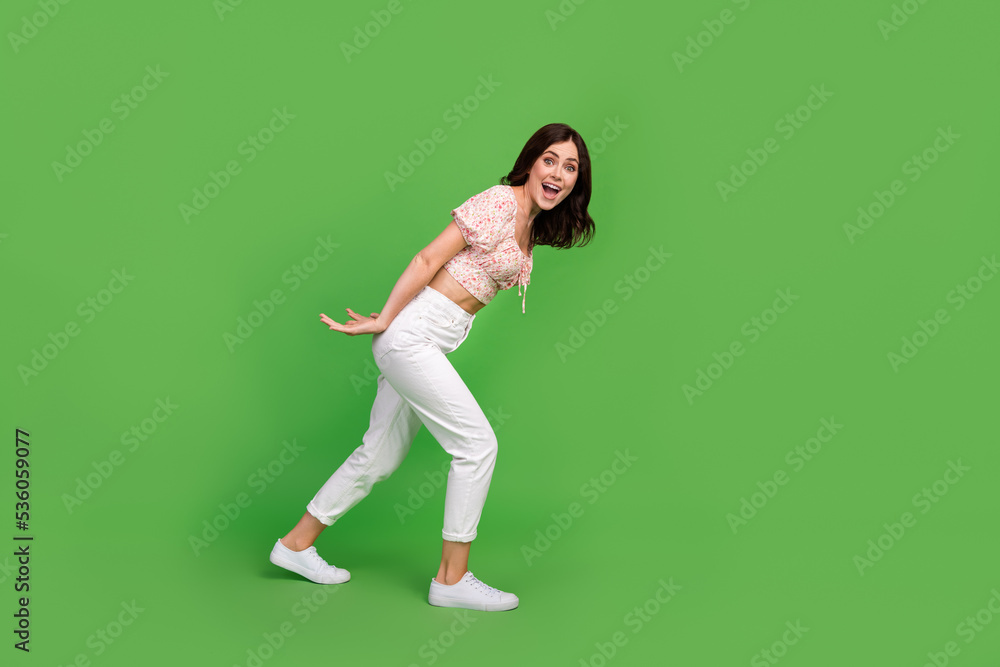 Full size photo of impressed nice woman with wavy hairdo wear white pants blouse hold empty space isolated on green color background Full size photo of impressed nice woman with wavy hairdo wear white pants blouse hold empty space isolated on green color background