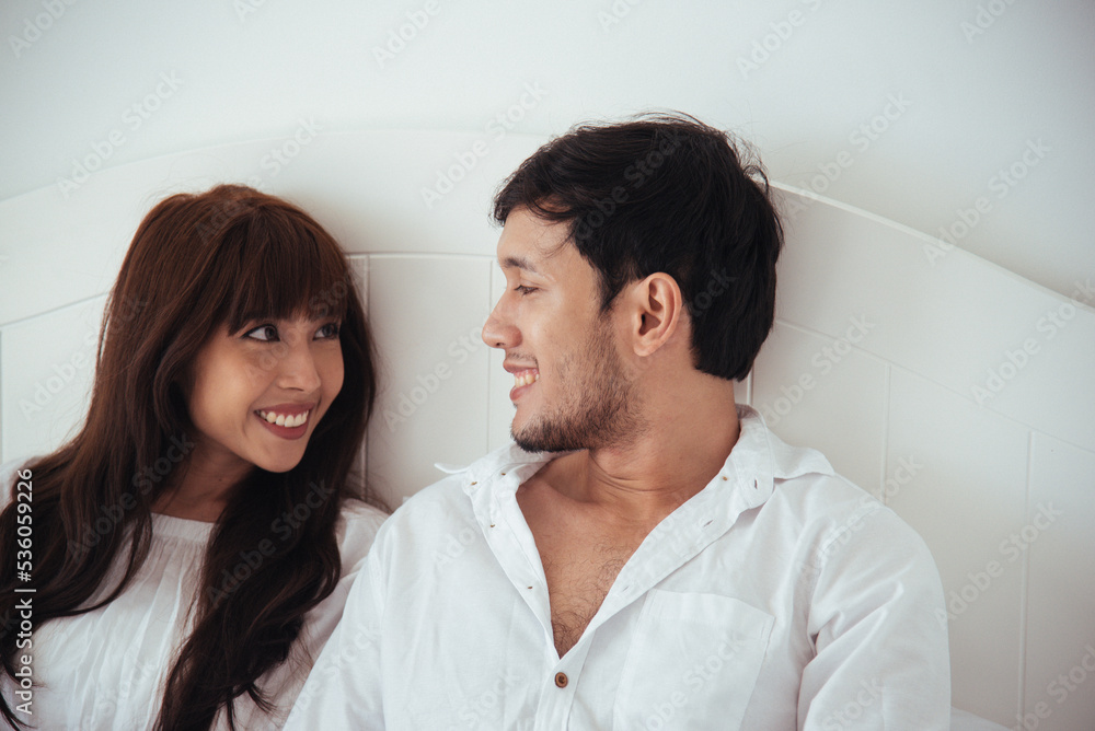 Asian couple laying and talking in bed together. Happy young lovely couple. Asian couple laying and talking in bed together. Happy young lovely couple.