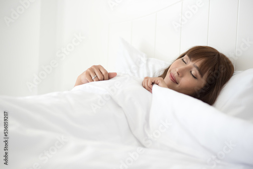 Young beautiful asian woman waking up after sleep and feels fresh in the morning in bedroom.