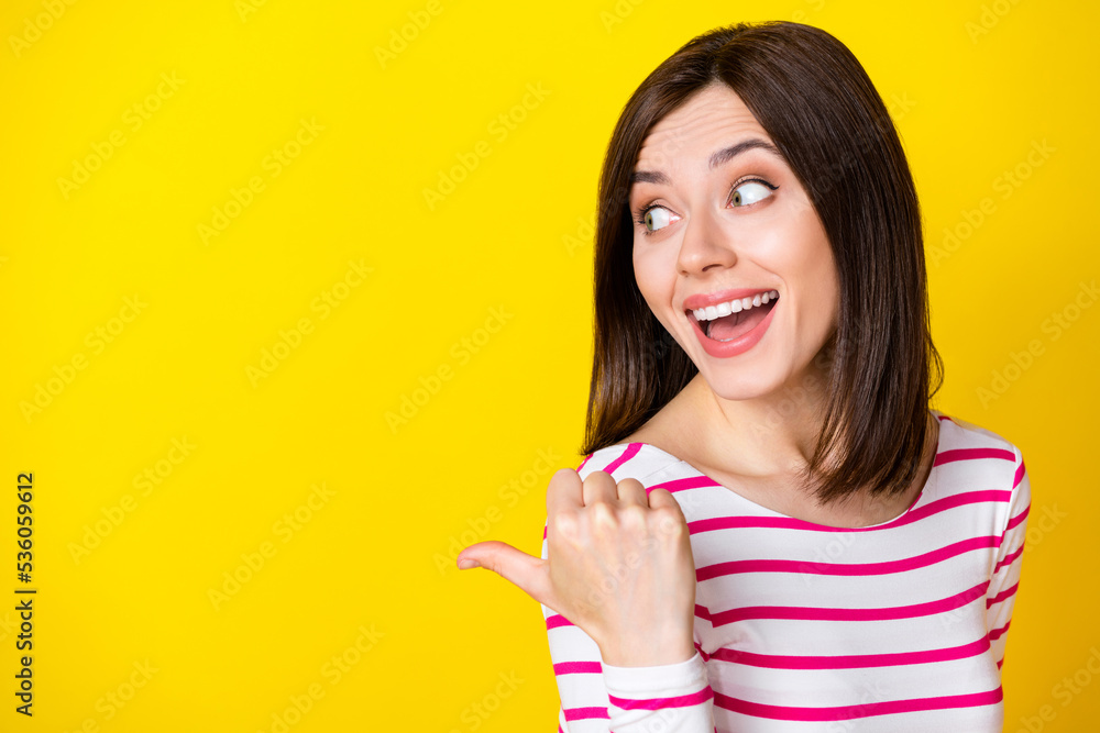 Closeup photo of young impressed attractive cute lady pointing looking empty space isolated on bright yellow color background Closeup photo of young impressed attractive cute lady pointing looking empty space isolated on bright yellow color background