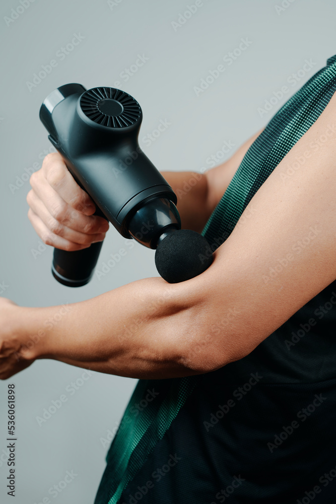 sportsman uses a massage gun on his arm
