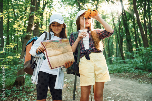 Using the map. Two girls is in the forest having a leisure activity, discovering new places
