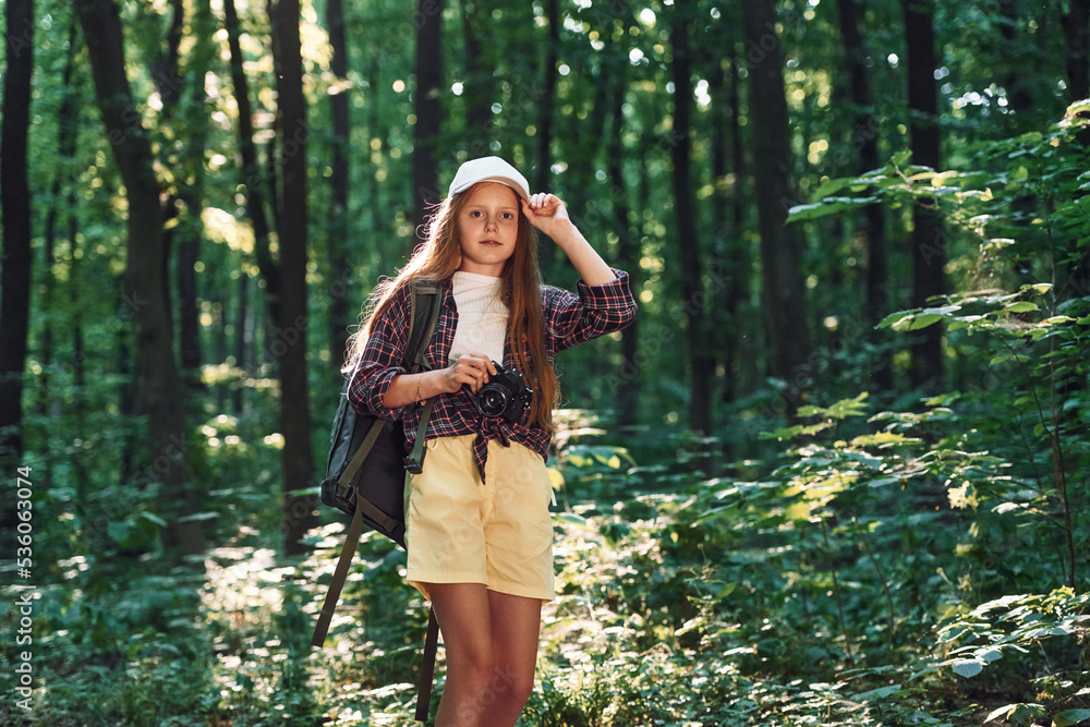 Young photographer with camera. Girl is in the forest at summer day time discovering new places Young photographer with camera. Girl is in the forest at summer day time discovering new places
