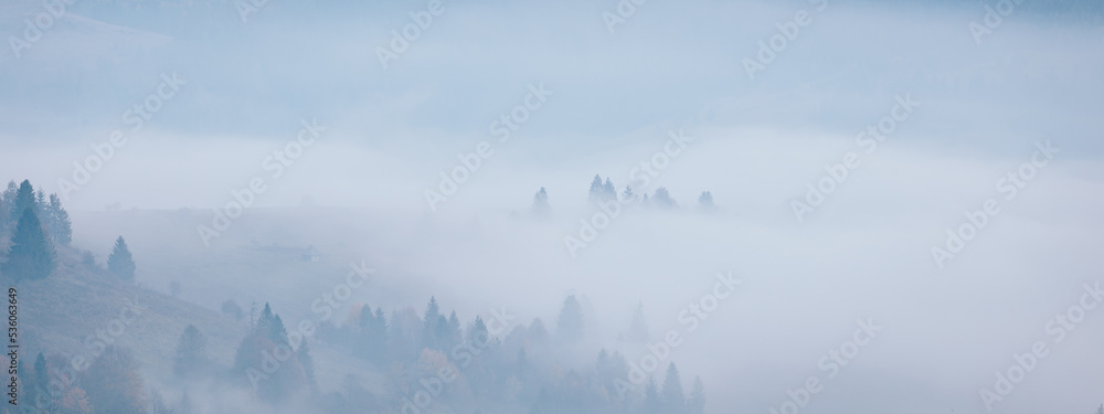 Mountain hills under morning fog at beautiful autumn foggy scenery. Wide panoramic landscape of Carpathian mountains. Ukraine. Mountain hills under morning fog at beautiful autumn foggy scenery. Wide panoramic landscape of Carpathian mountains. Ukraine.
