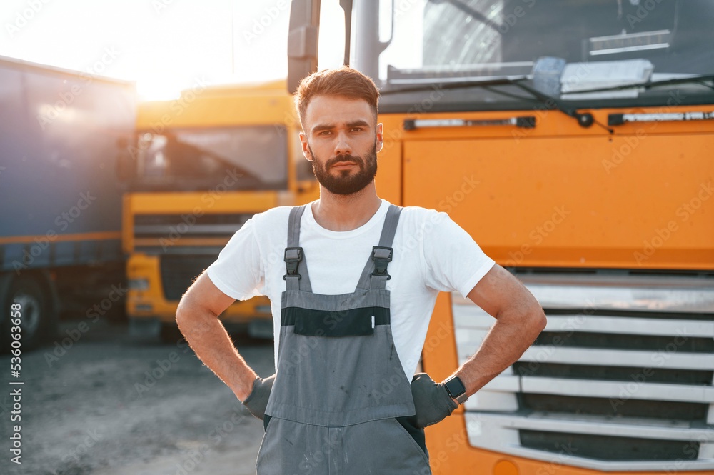 Standing and posing for the camera. Man in unifrom doing service for big truck vehicle Standing and posing for the camera. Man in unifrom doing service for big truck vehicle