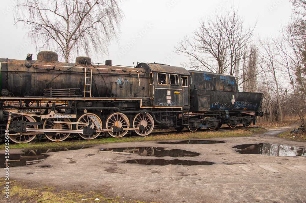 Naklejka premium An old and dilapidated historic PKP steam locomotive standing on a siding on a gloomy autumn day. Rail.