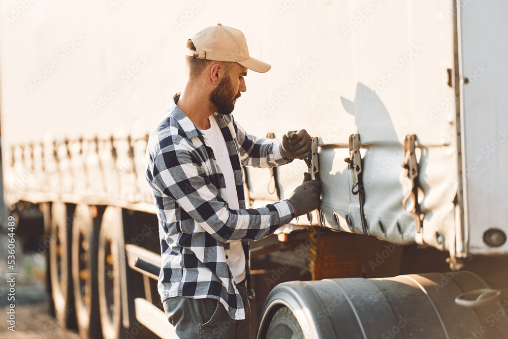 Ready for the ride. Young truck driver is with his vehicle at daytime Ready for the ride. Young truck driver is with his vehicle at daytime