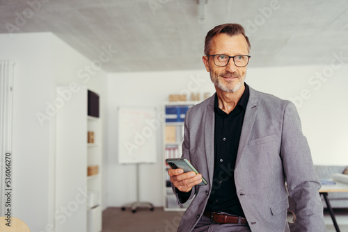 Close up view of smiling man professional user standing at home office holding smart phone in hands text message using cellphone application technology modern gadget concept. Copyspace.