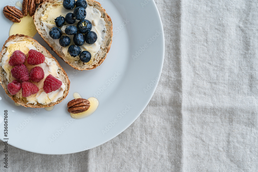 Breakfast, sandwiches with cheese spread, blueberry, raspberry fruits, honey and pecan, top view Breakfast, sandwiches with cheese spread, blueberry, raspberry fruits, honey and pecan, top view
