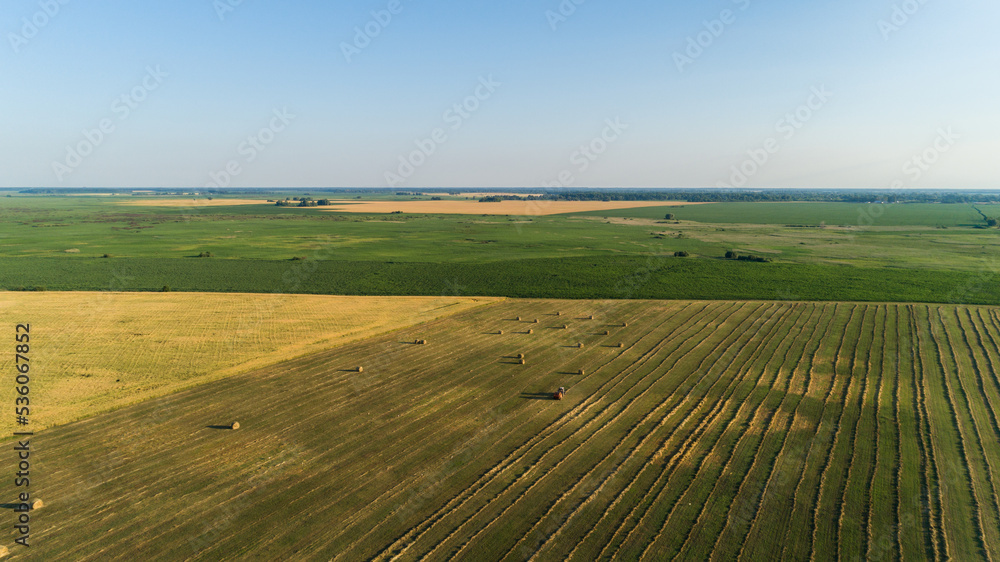 Aerial view tractor with baling machine making silage bales on farmland at agricultural field. Drone shot haystack and harvesting dry grass for agriculture. Farmers season to cut and harvest crops Aerial view tractor with baling machine making silage bales on farmland at agricultural field. Drone shot haystack and harvesting dry grass for agriculture. Farmers season to cut and harvest crops