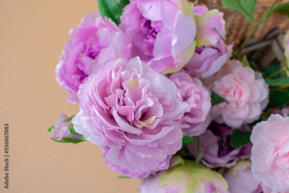 bouquet of pink roses in a wicker basket on a beige background, close-up