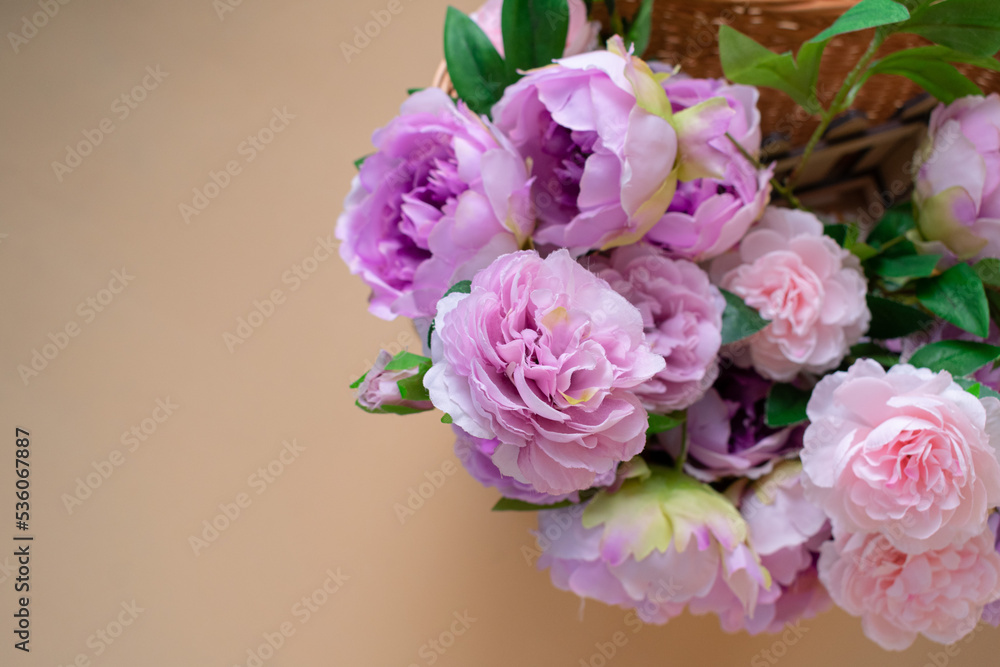 bouquet of pink roses in a wicker basket on a beige background, close-up