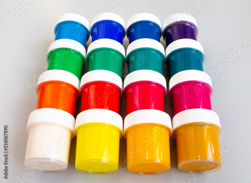 A set of closed jars with gouache of different colors are laid out in rows on a gray background. Hobby - drawing